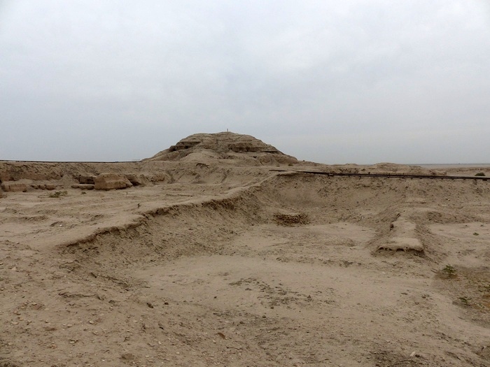 Present-day view across excavated ground towards the surviving Eanna ziggurat mound at Uruk.