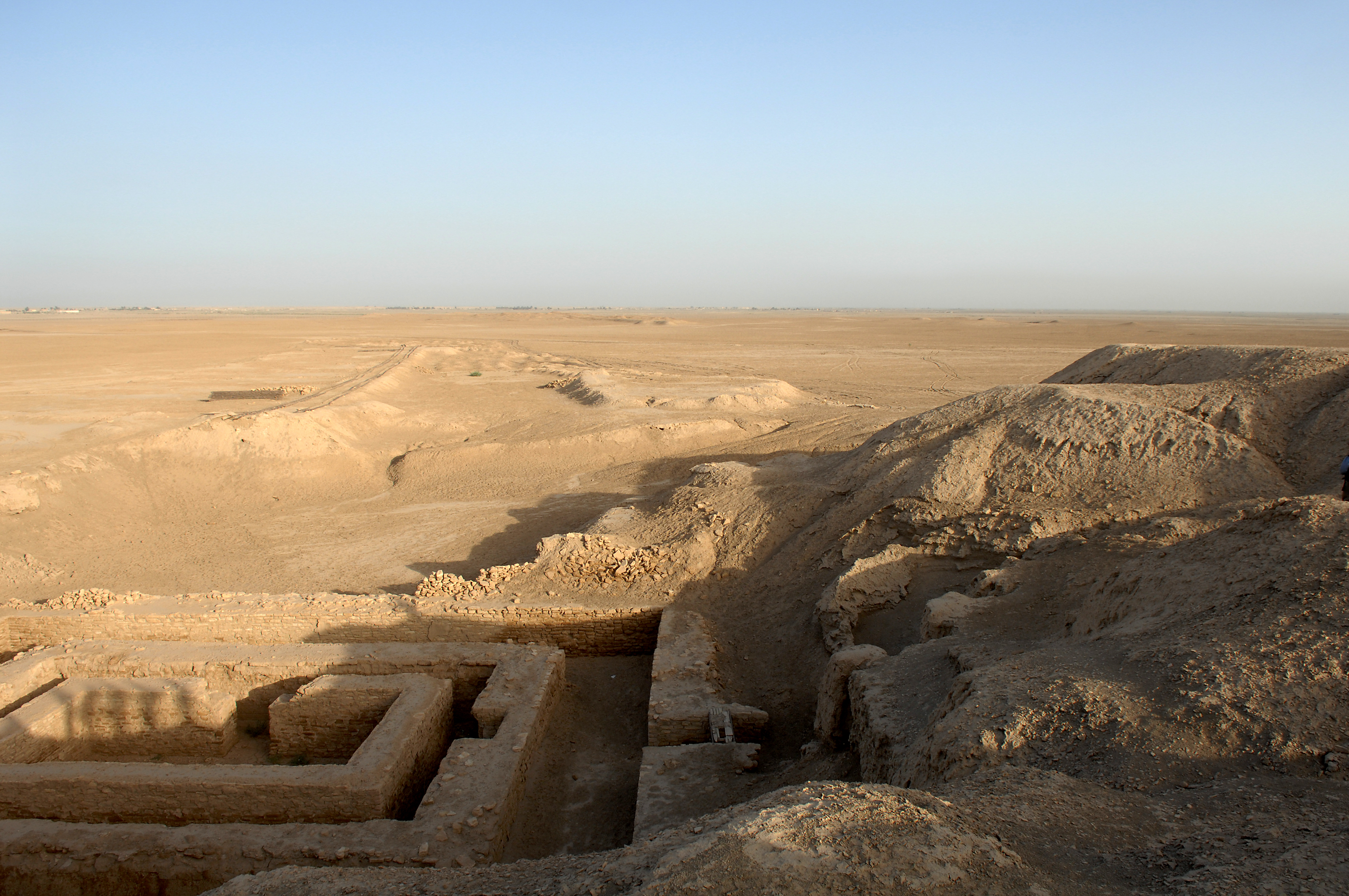 Excavated mud-brick walls and low mounds at Uruk, with an open plain extending to the horizon.