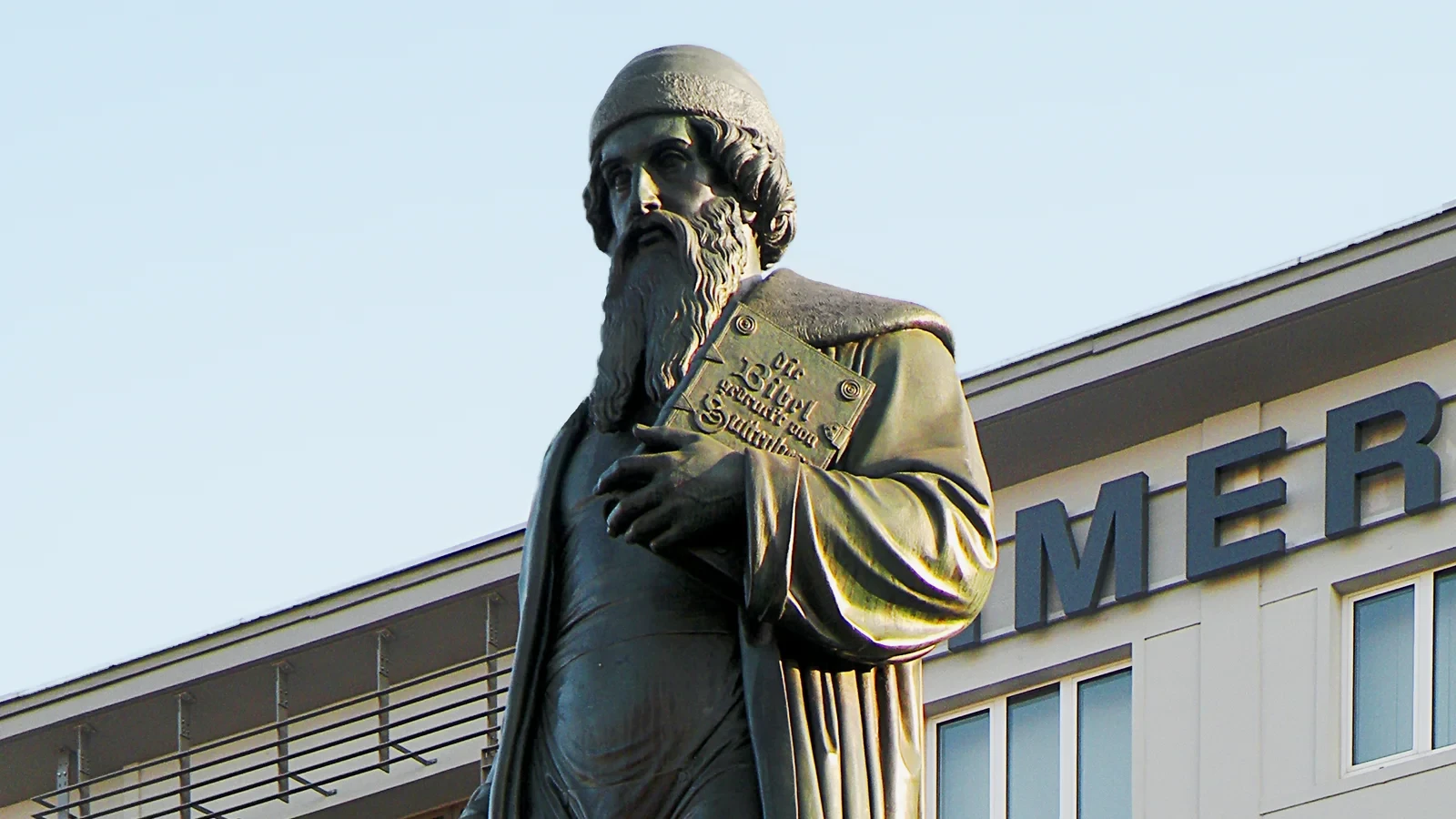 The head and upper body of the bronze Gutenberg memorial in Mainz, with a book held against its chest.