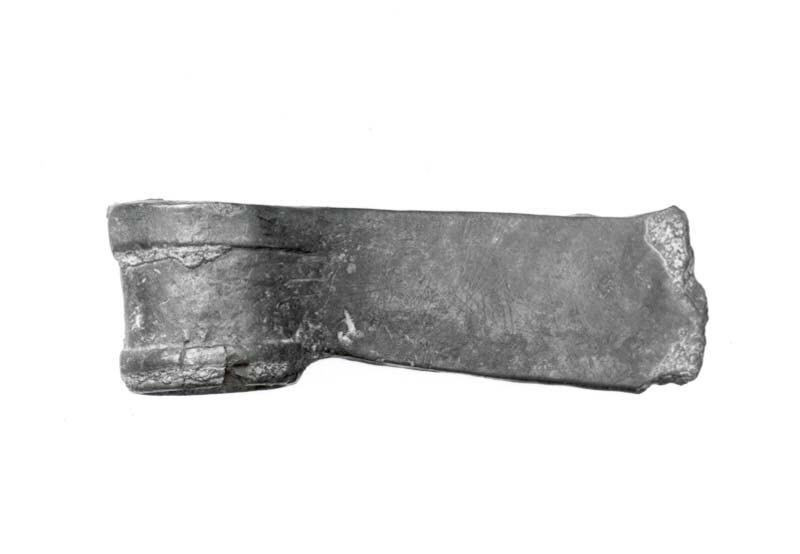 A surviving bronze axe head has a socket at one end and a broad curved cutting edge at the other.