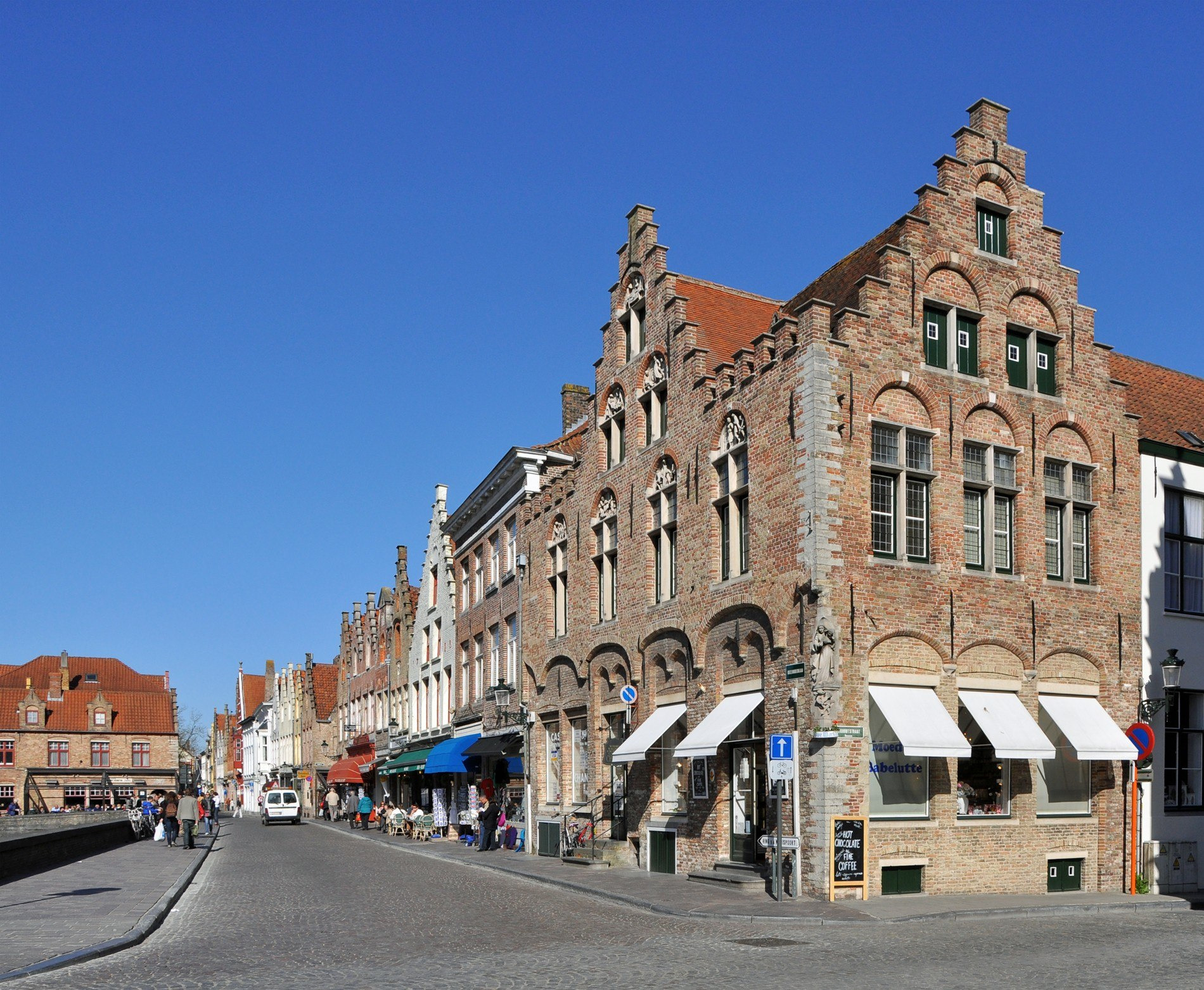 A street curves past a tall brick corner building with stepped gables at the Rozenhoedkaai.