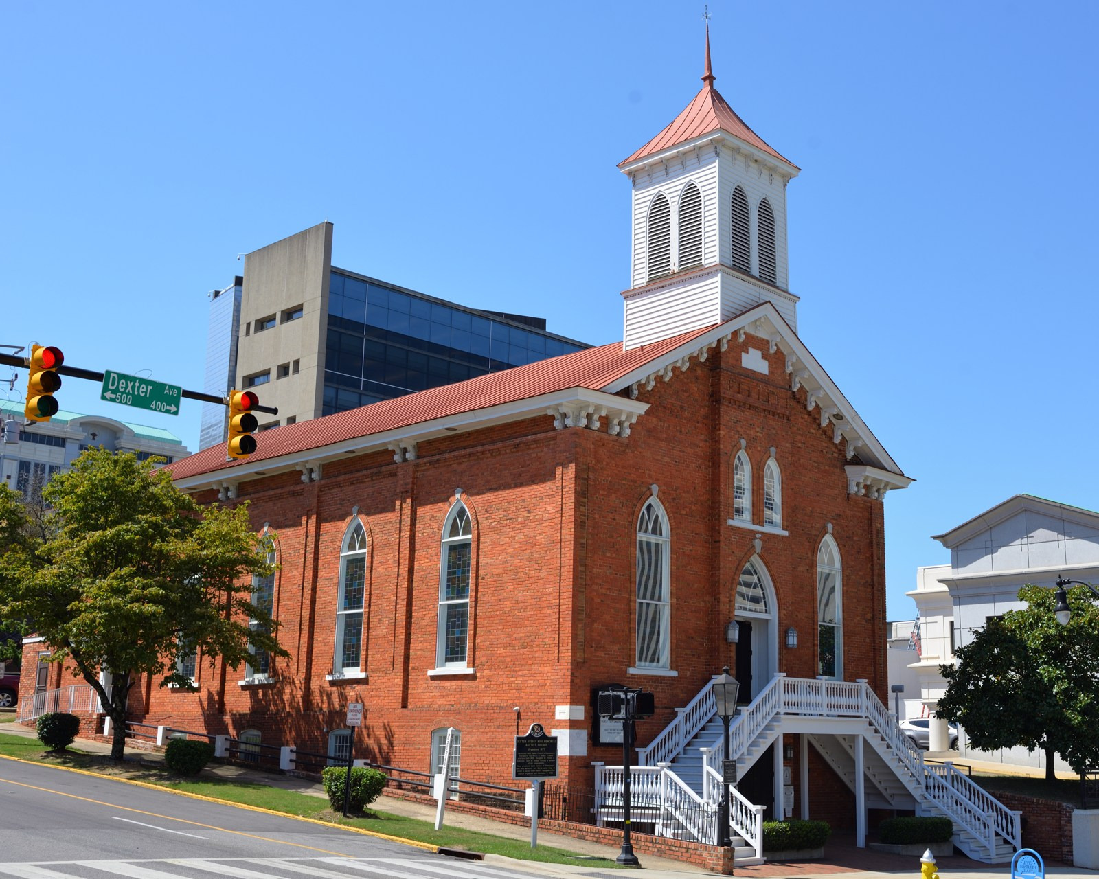 Dexter Avenue Baptist Church has red brick walls, front steps and a white bell tower.