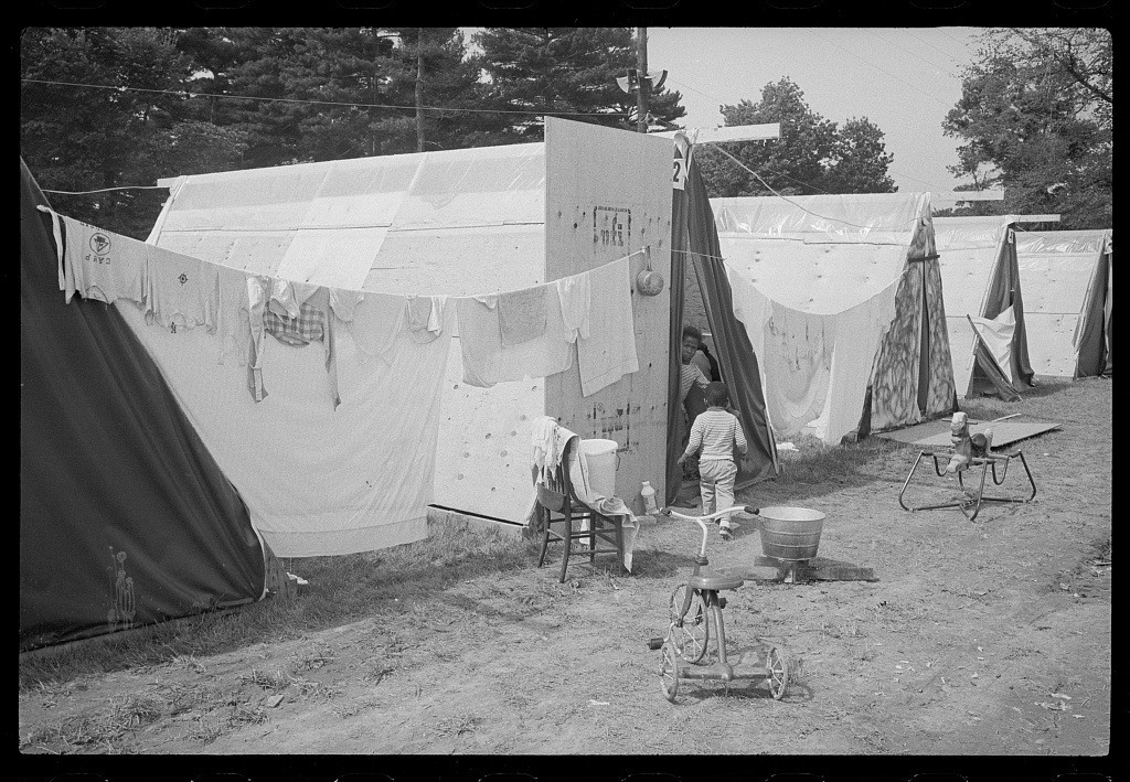 Children beside canvas-covered shelters, hanging laundry and a bucket at Resurrection City.