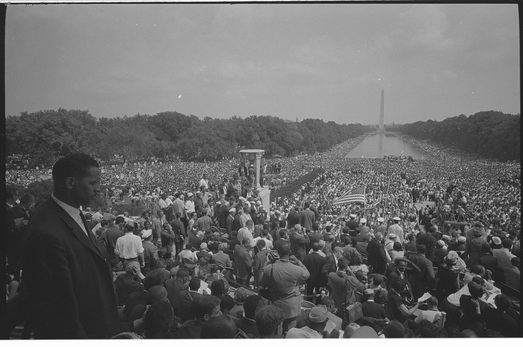 A crowd extends around the Reflecting Pool toward the Washington Monument, seen from the Lincoln Memorial.