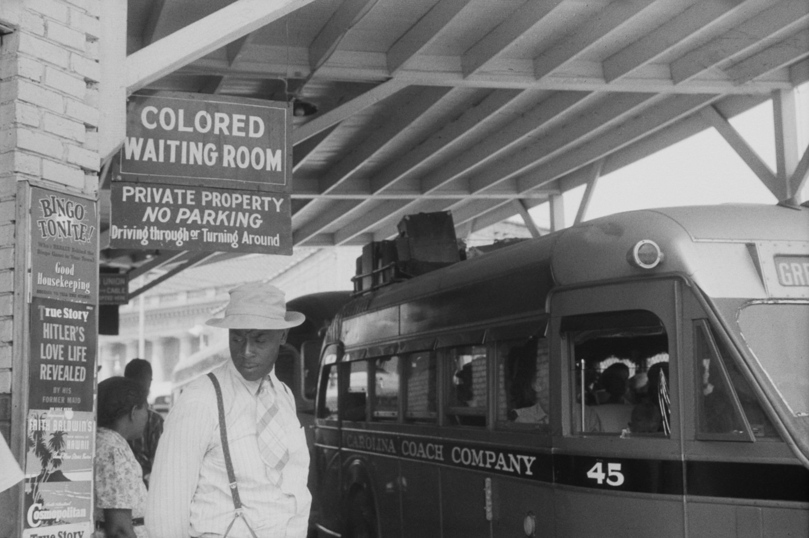 People stand beside a bus under a sign marked Colored Waiting Room in Durham.