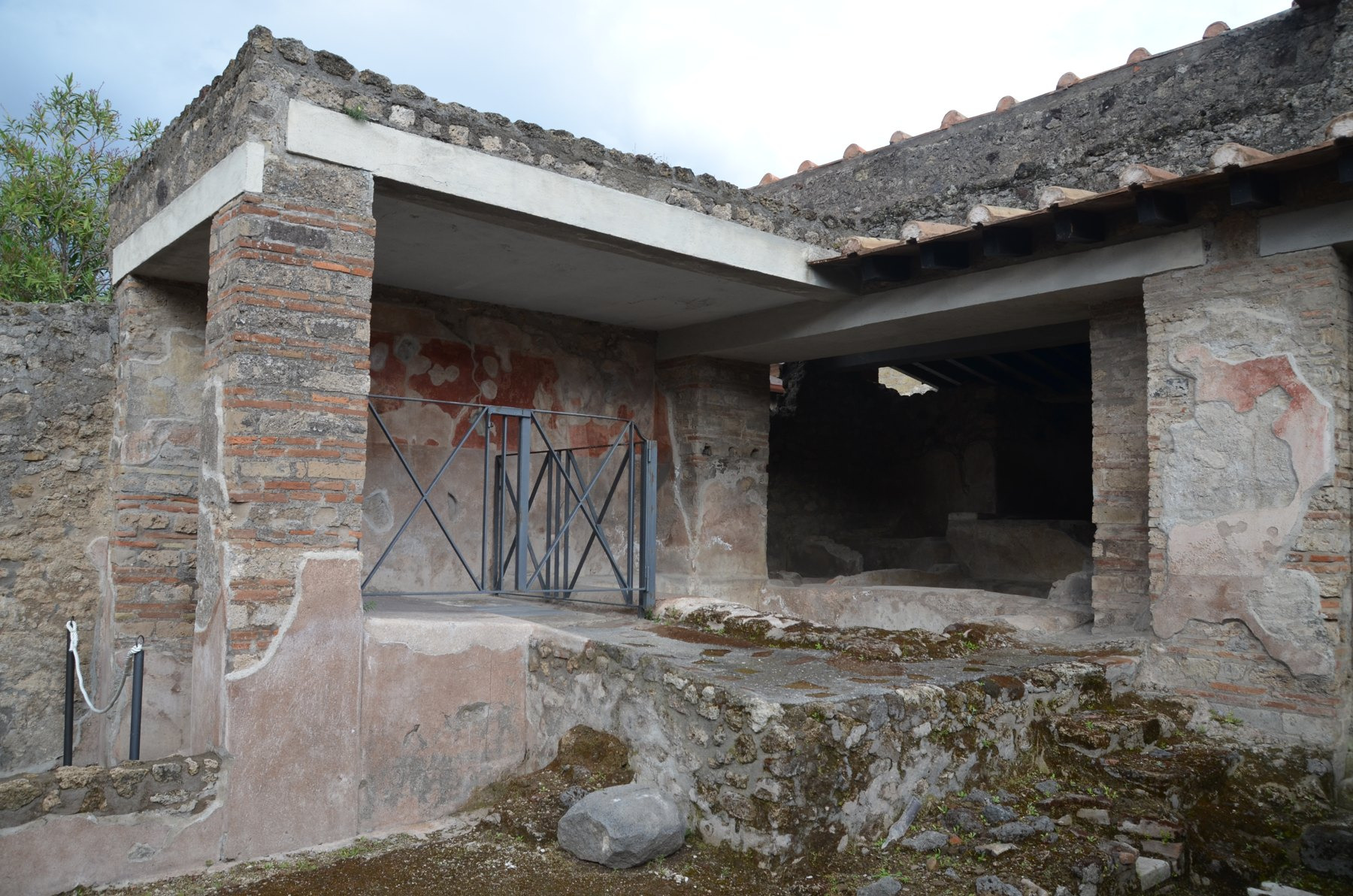 A Pompeian courtyard contains surviving masonry basins beside painted walls.