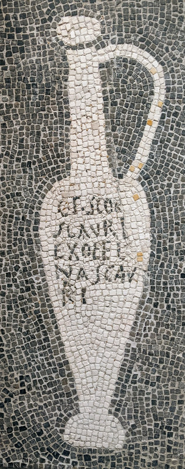 A black-and-white ancient mosaic depicts a handled fish-sauce bottle with lettering across its body.