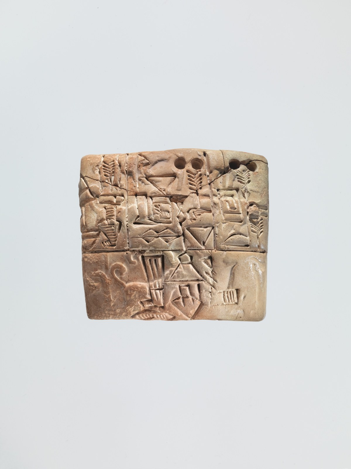 A small rounded clay tablet carries incised signs, circular impressions and traces of impressed imagery.