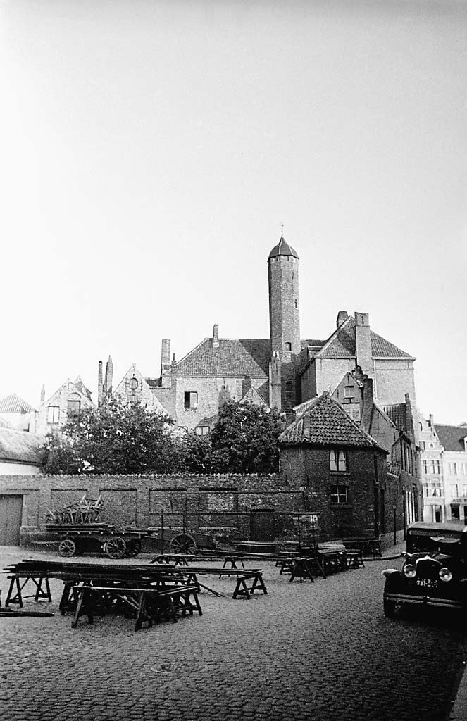 A black-and-white view of Oosterlingenplein with tables in the foreground and a tower beyond the buildings.