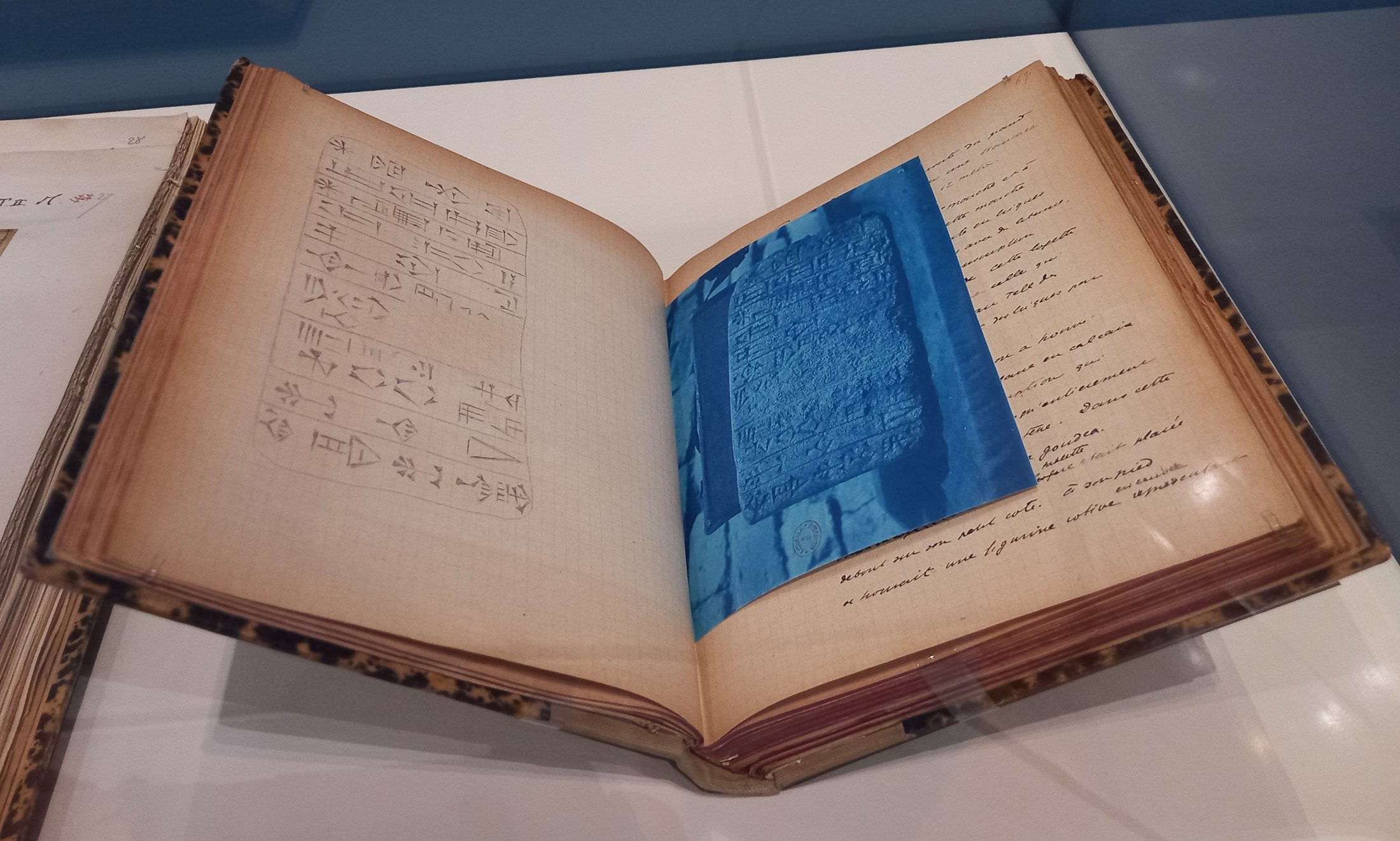 An excavation journal page combines a hand-drawn cuneiform copy with a blue photographic print.