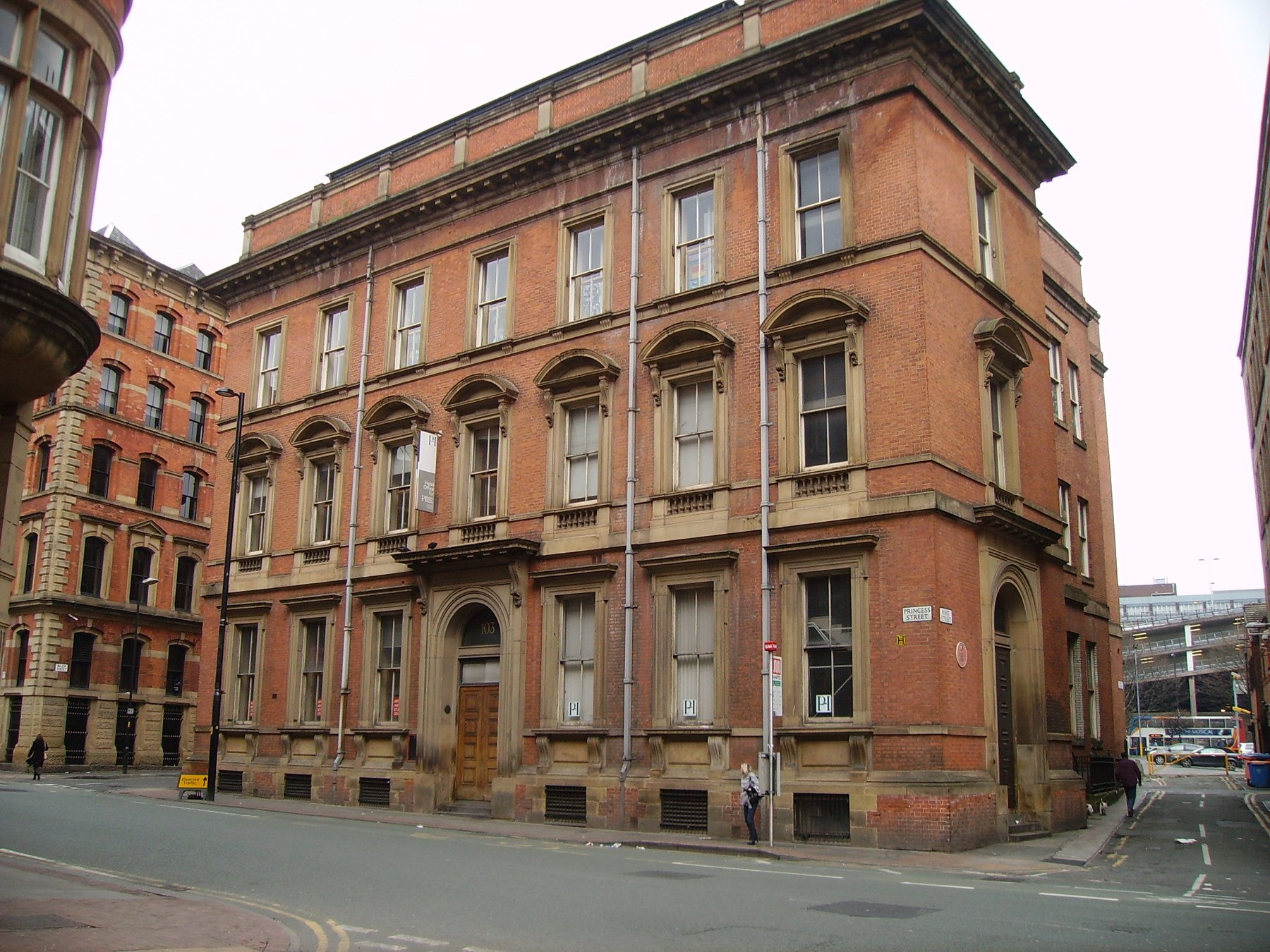 A modern street photograph shows the red-brick Mechanics’ Institute building in Manchester.