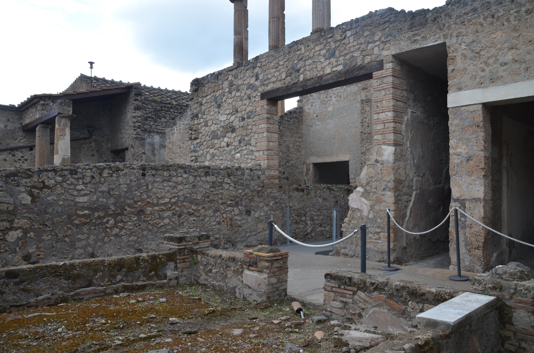 Low masonry divisions and basins occupy the rear of the Fullonica of Stephanus, beside walls, columns and doorways.