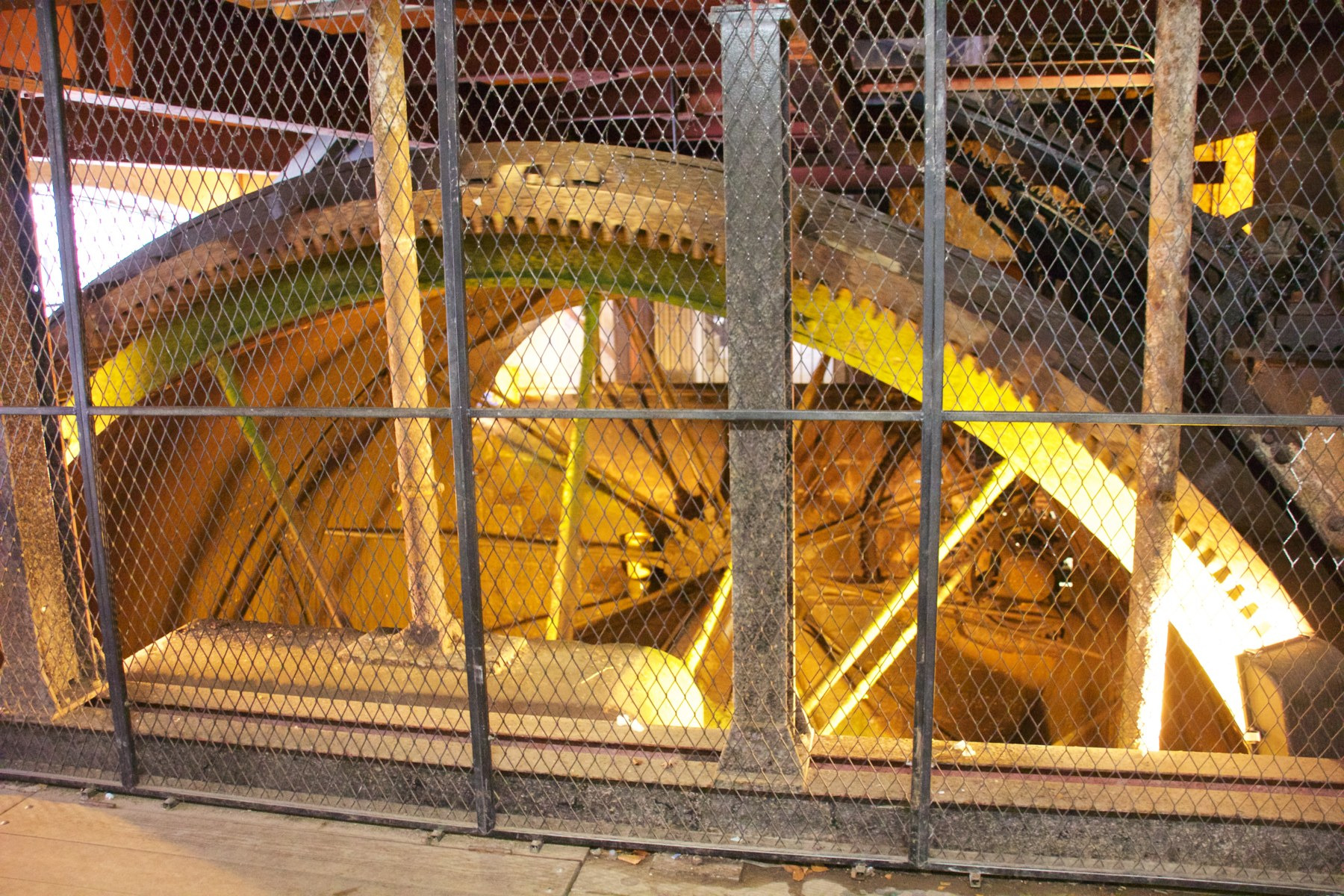 A large preserved waterwheel at Quarry Bank behind a modern protective barrier.