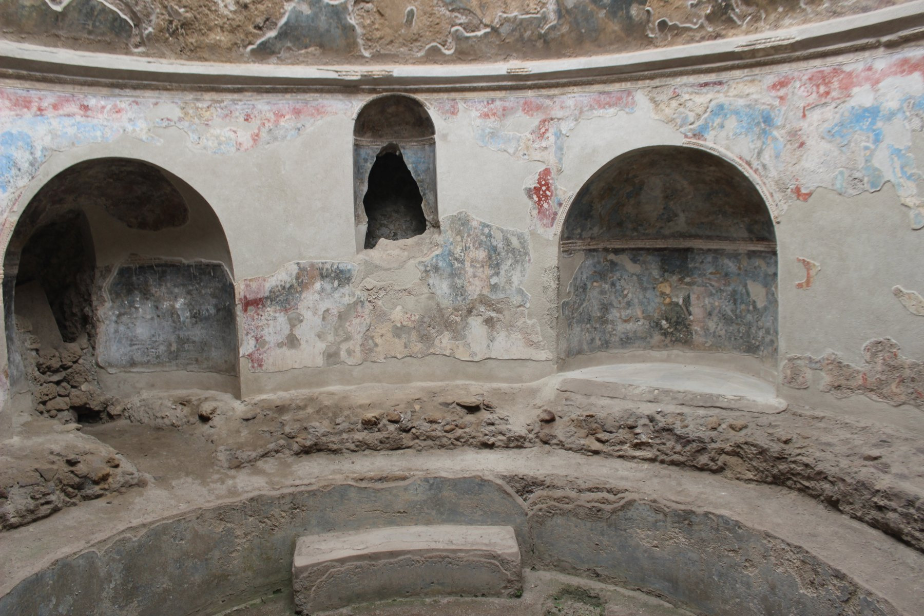 Arched niches and surviving painted plaster surround the circular cold-water basin in the Stabian Baths.