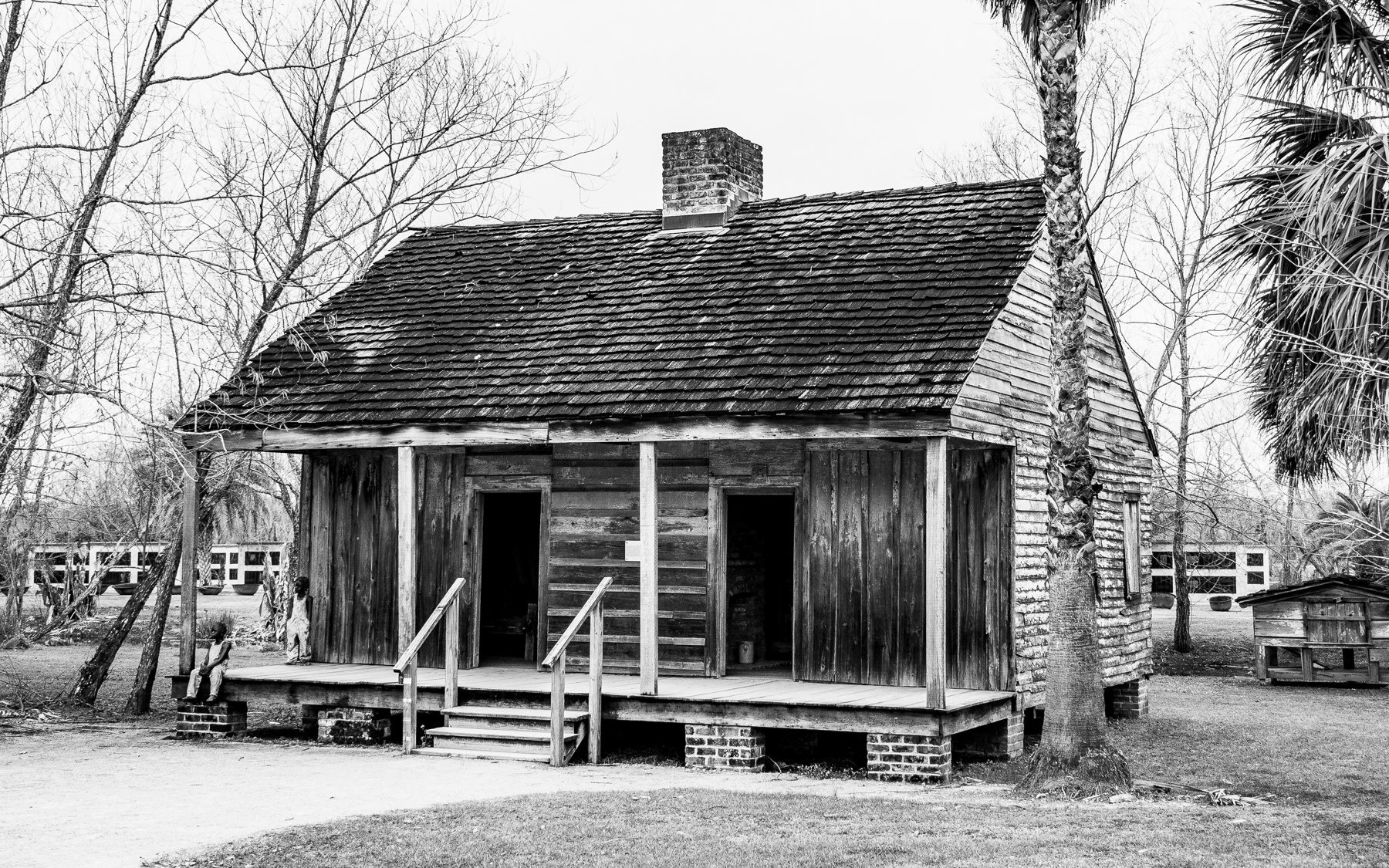 A 2020 black-and-white photograph shows cabins displayed at Whitney Plantation Museum in Louisiana.